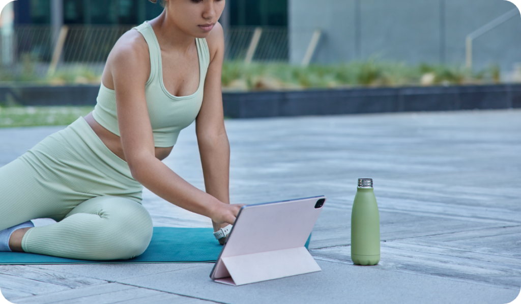 donna seduta a terra in tenuta da palestra che usa un tablet